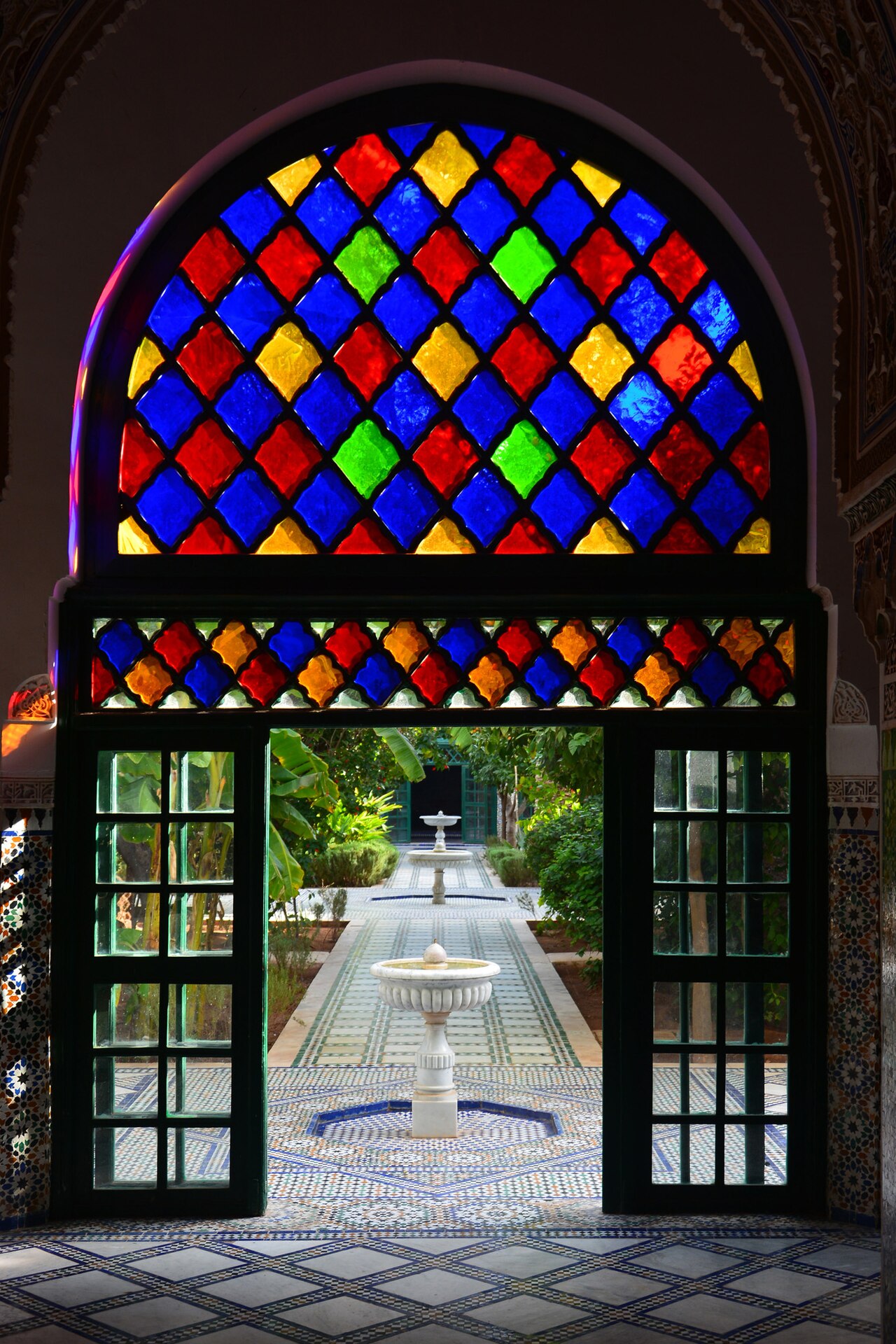 A stained-glass arch framing a garden and fountain at Bahia Palace